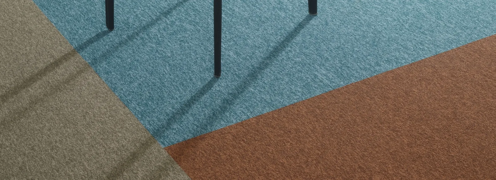Tapijttegels in grijs, blauw en roestbruin gelegd in diagonale vlakken onder een tafel