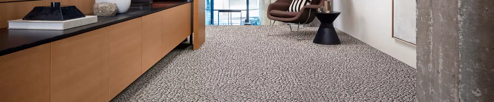 Tapijttegels voor kantoor die lijken op een grindpad, beige van kleur, gelegd in een moderne kantoorruimte.