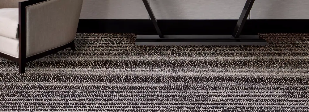 Tapijttegels in zwart-wit melee onder een fauteuil