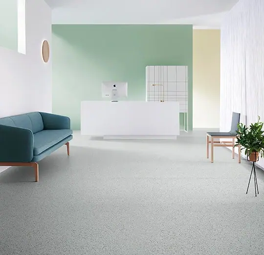 Forbo Sphera Essence homogene vinylvloer in lichtgrijze granietsteenlook, geïnstalleerd in een moderne zakelijke ruimte met strakke witte wanden en minimalistische inrichting.