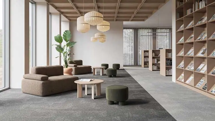 Desso Arable 9960_9920 tapijtvloer in grijstinten in een moderne bibliotheek met loungehoek en boekenkasten.