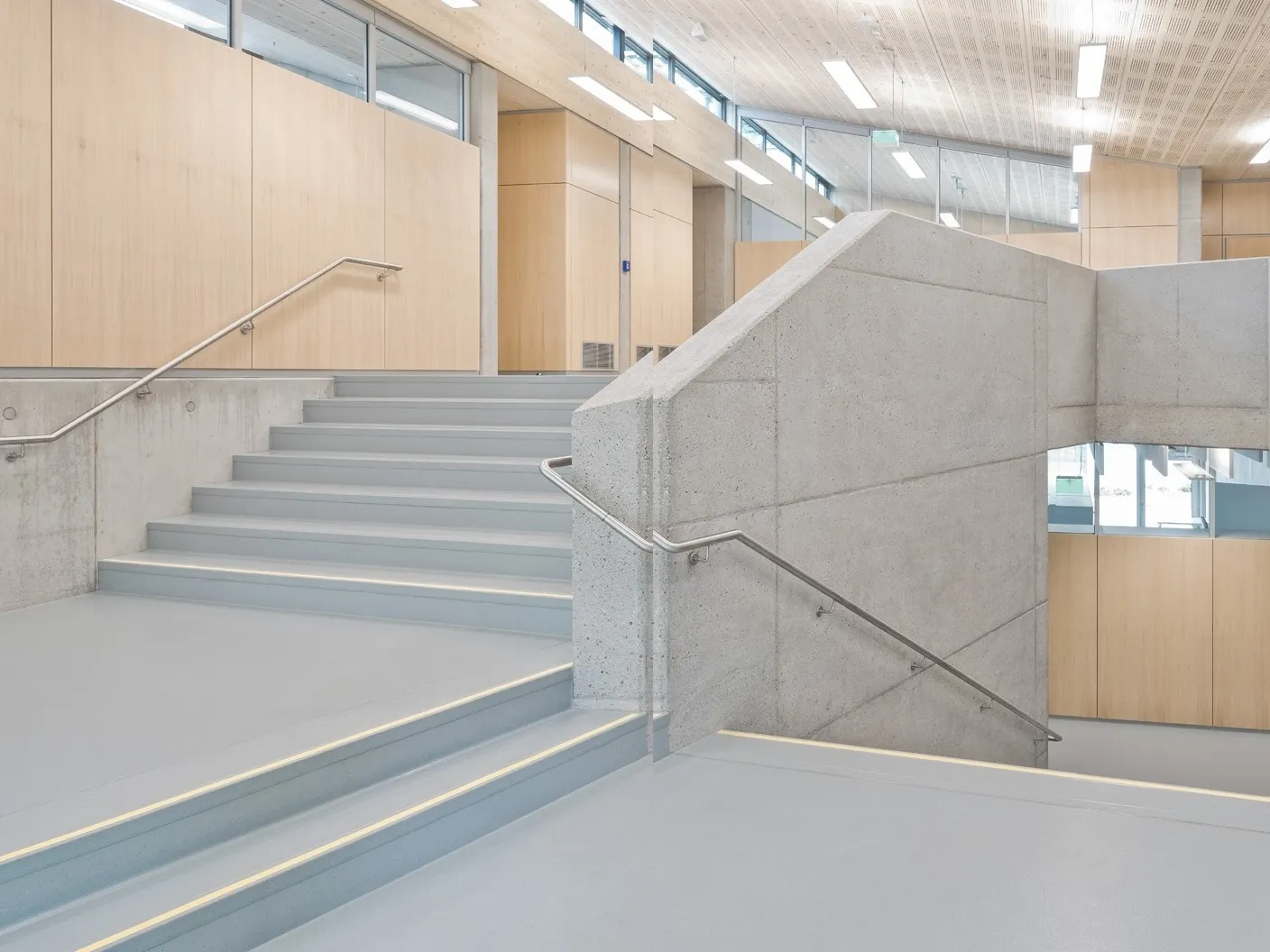 Lichtgrijze Norament 926 satura trapvormen in kleur 5114 in een open trappenhuis van een school