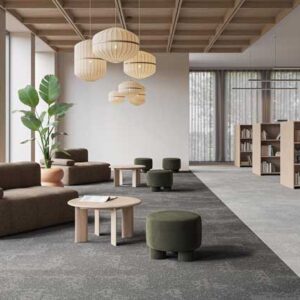 Desso Arable 9960_9920 tapijtvloer in grijstinten in een moderne bibliotheek met loungehoek en boekenkasten.