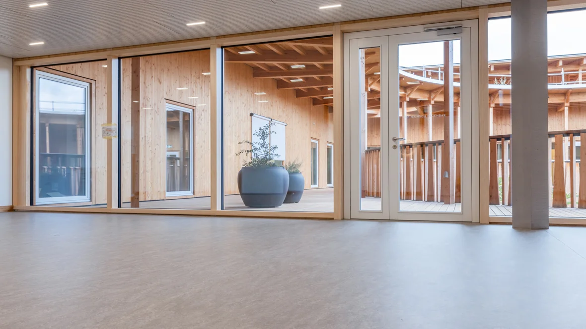 Lichtgrijze linoleumvloer in de entree van een kinderopvang, met natuurlijke lichtinval en kindvriendelijke inrichting.